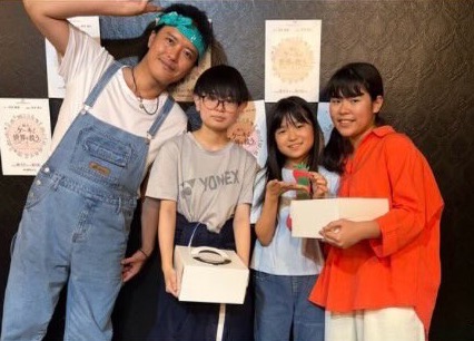 ケーキの箱を手にした出演者と子どもたち
