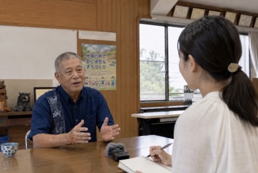 地域の方のお話を、メモを取りながら聞く出演者